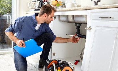 plumber looking under sink to quote job 